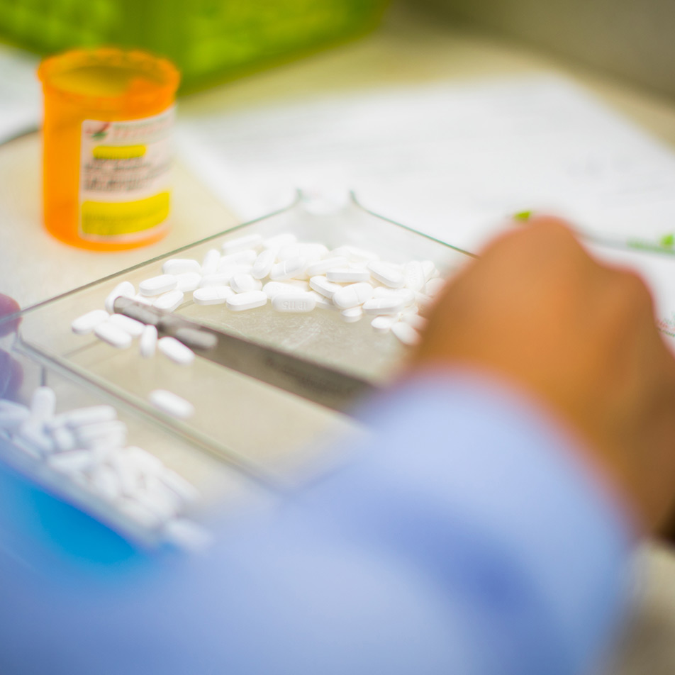 A pharmacist sorts pills in a tray.